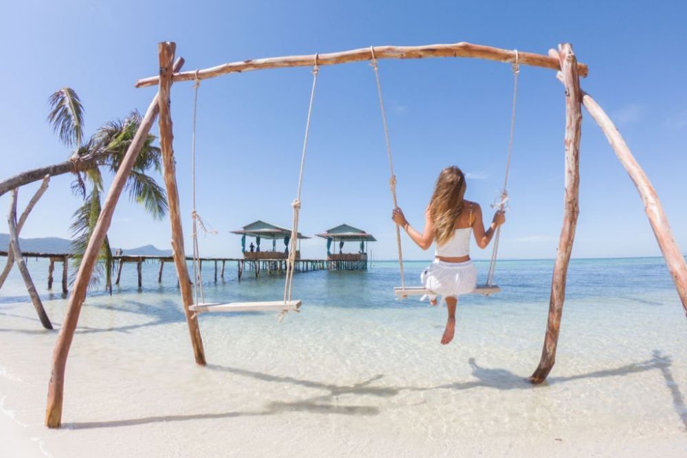 Un turista è seduto su un'altalena sulla spiaggia di Phu Quoc.